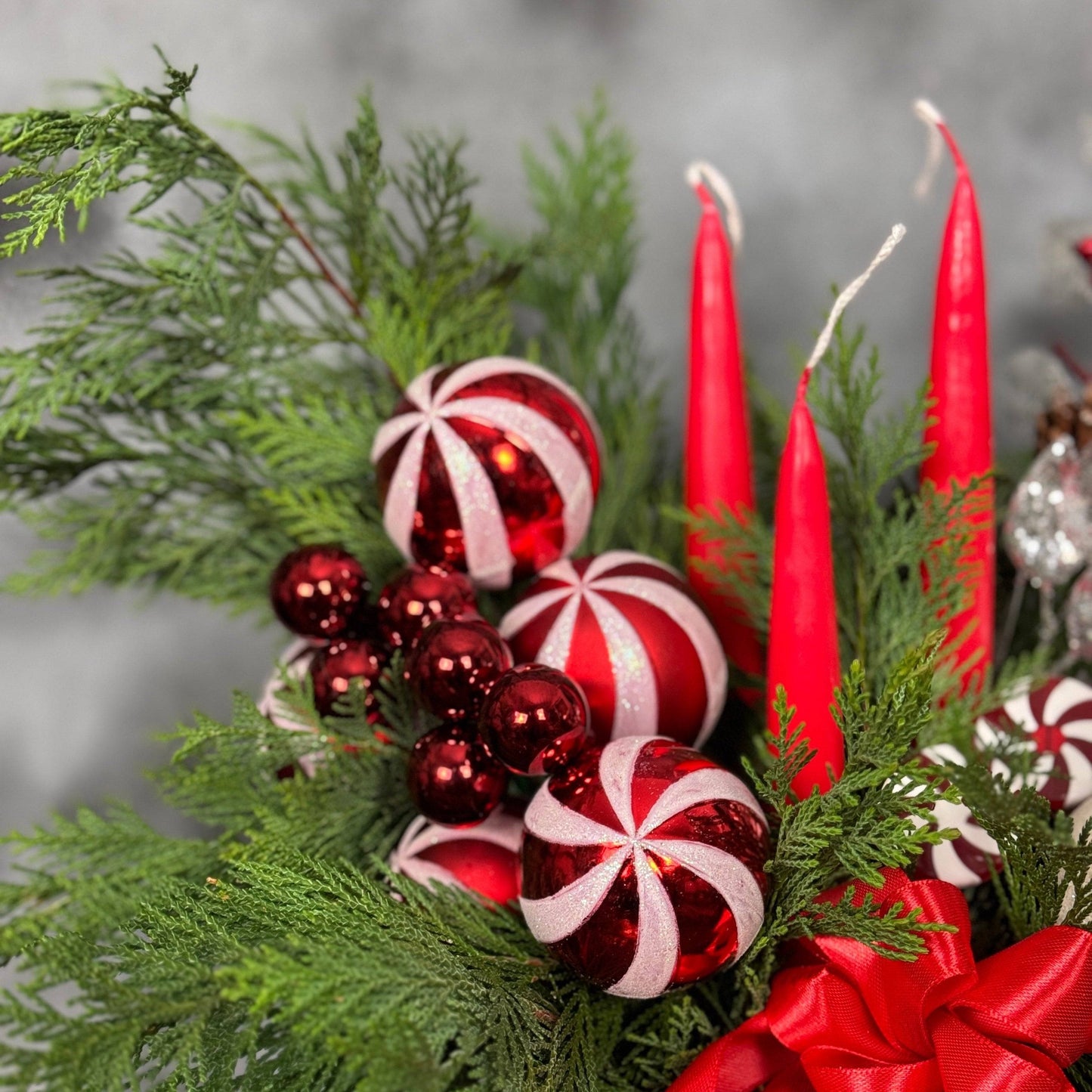 Aranjament de sărbători cu lumânări, decorațiune ren și accente strălucitoare roșii și argintii.