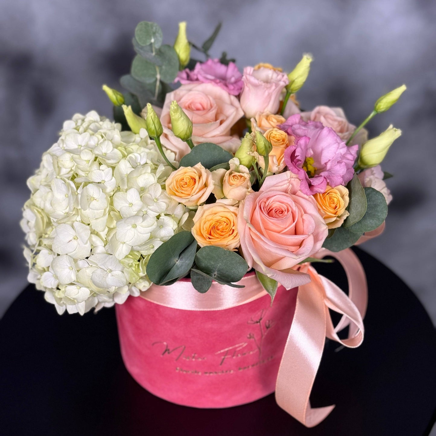 Aranjament floral pastelat în cutie de catifea roz, cu trandafiri, hortensie și eustoma.