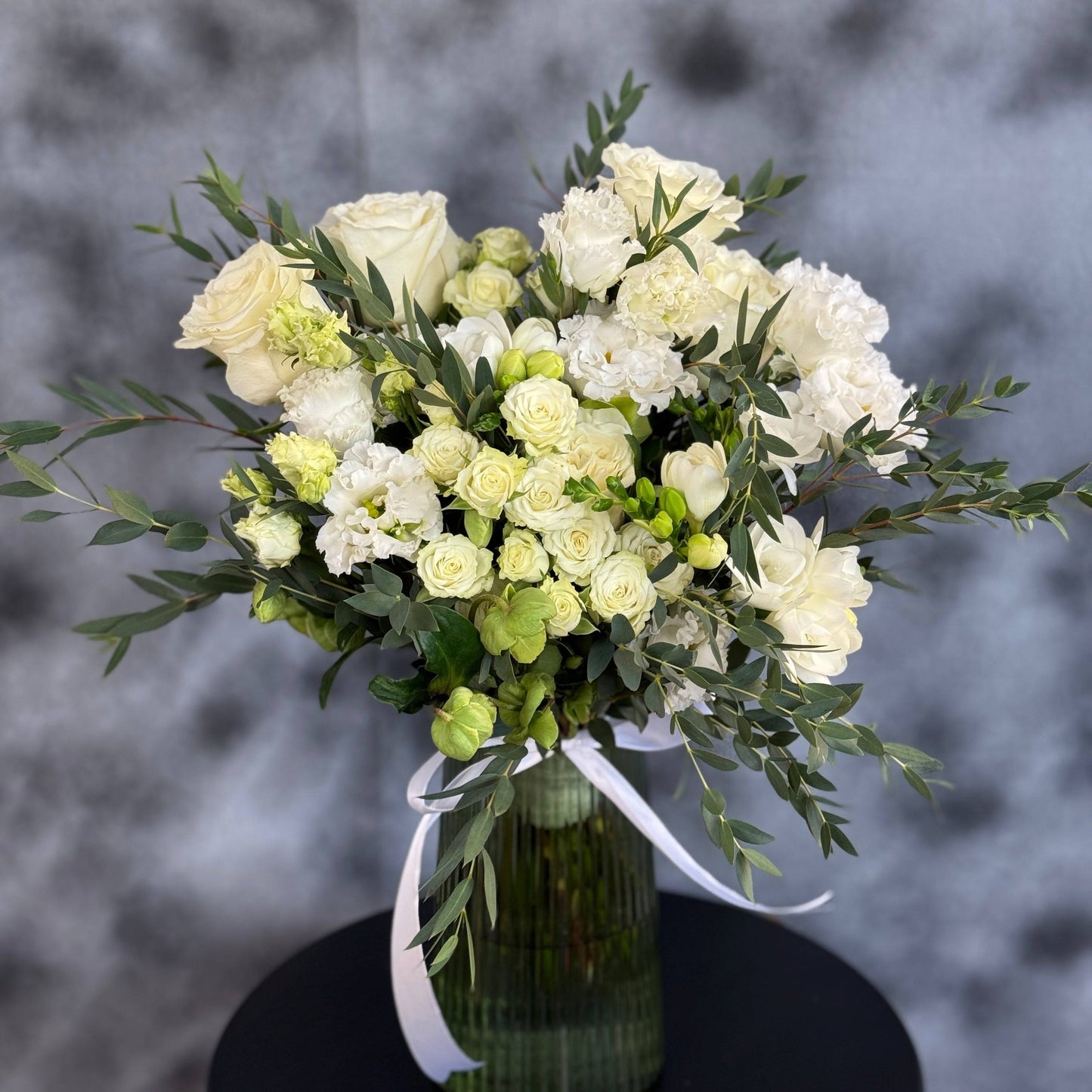 Buchet de mireasă elegant cu trandafiri albi, frezie, eustoma, gypsophila și ruscus, realizat de Mister Flower pentru nunți în Cluj și Florești, aducând rafinament și puritate în ziua specială.