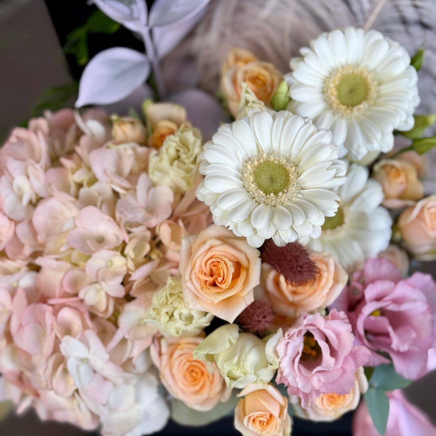 hortensii, trandafiri, gerbera, lisianthus și pampas, decorat cu o fundă roz satinată.