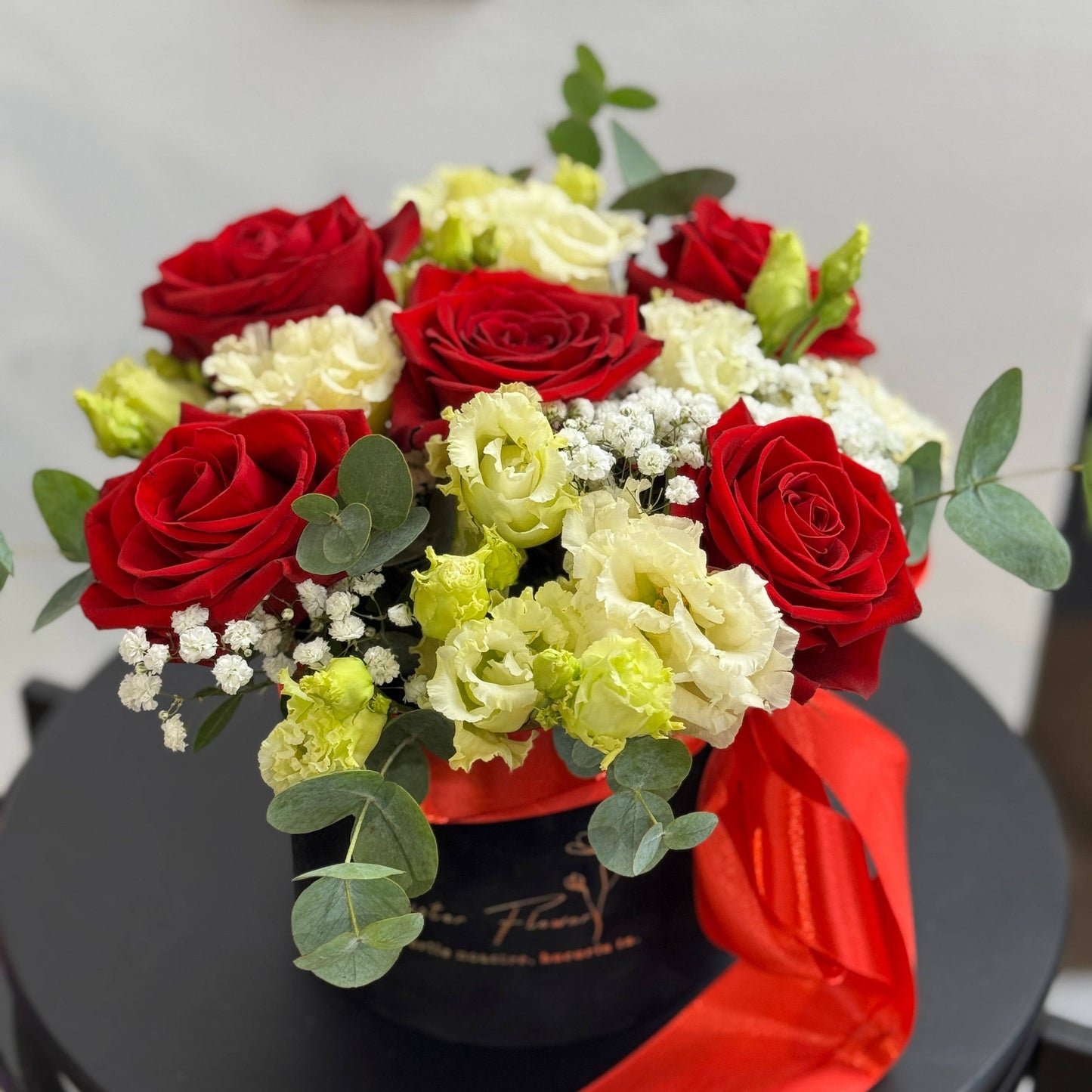 Buchet elegant cu trandafiri roșii, gypsophila, eustoma pastel si eucalipt toate intr-o cutie de catidea neagra. Aranjament elegant pentru aniversare, iubita, ziua sotiei. Florarie Floresti Cluj