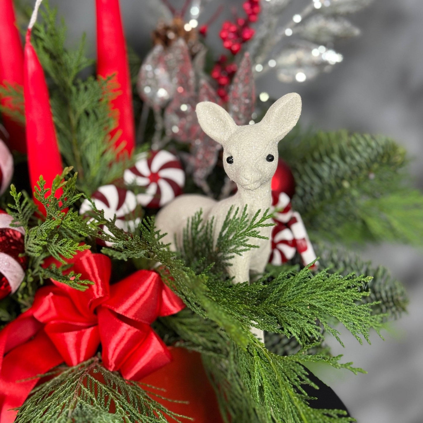 Decor de Crăciun cu elemente naturale din brad, globuri festive și panglică roșie elegantă.